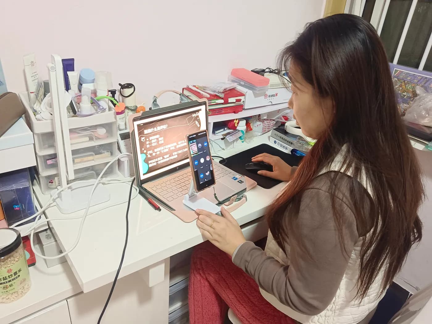 Working with a presentation on a laptop, a phone on a stand alongside