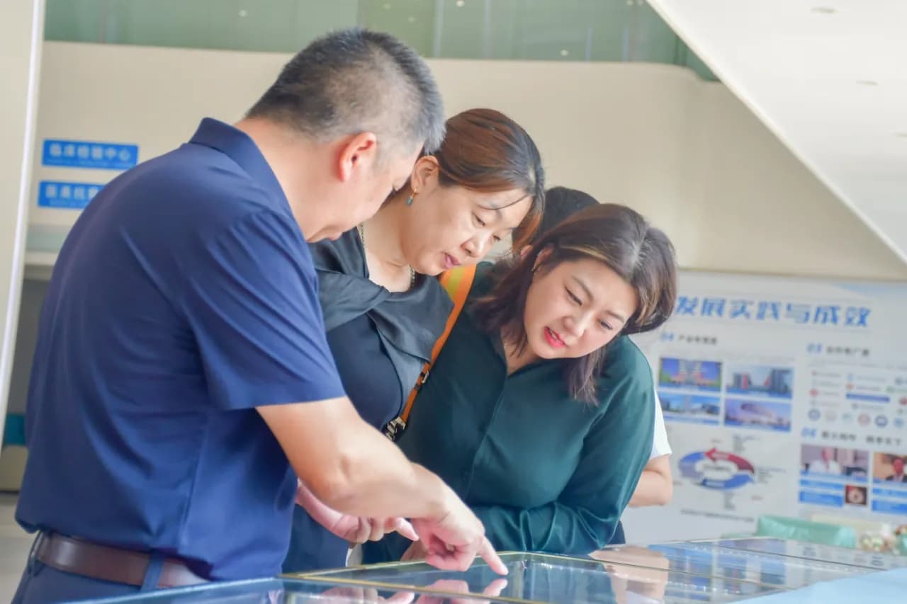 A group by a glass display case in a hall, a man pointing at something inside