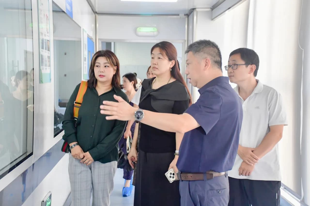 A group by glass-fronted information boards in a corridor, a man explaining something