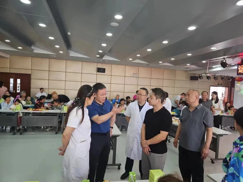 医院大厅里的节日活动：工作人员与家庭围坐在摆好的餐桌旁