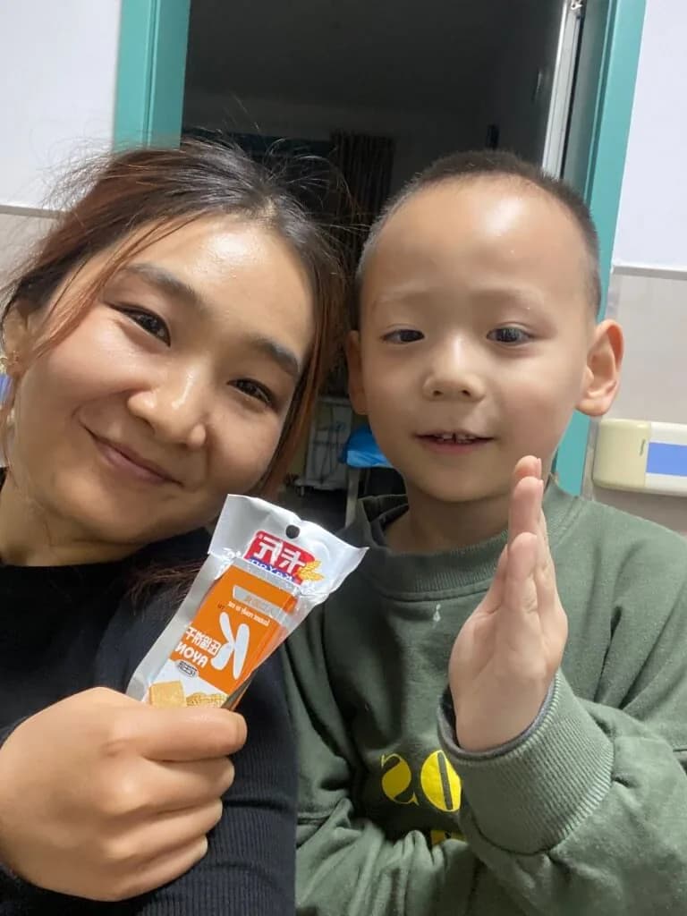 医院科室里的合影：一位女士和一个男孩手里拿着点心