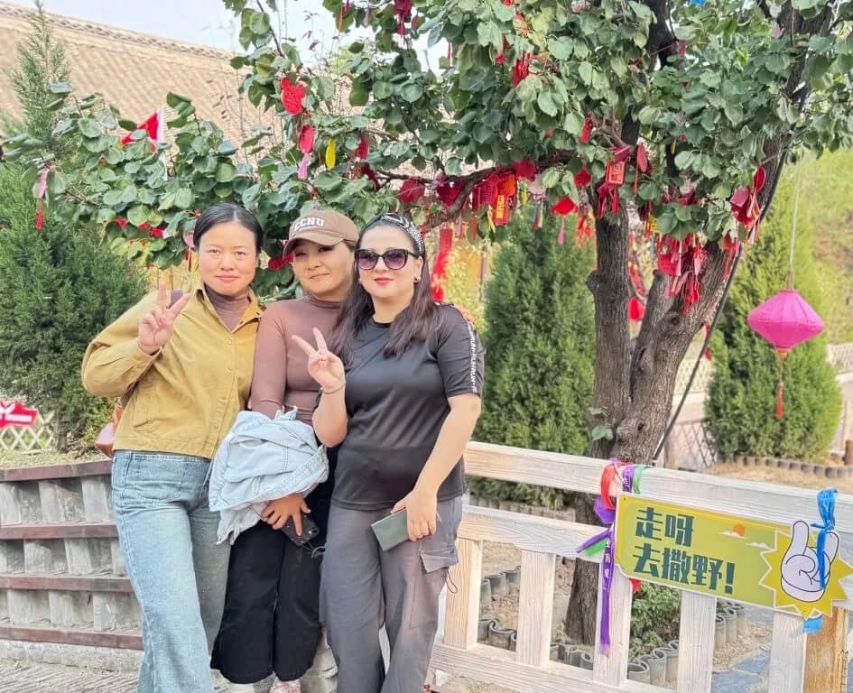 在挂满红色丝带的树旁的合影