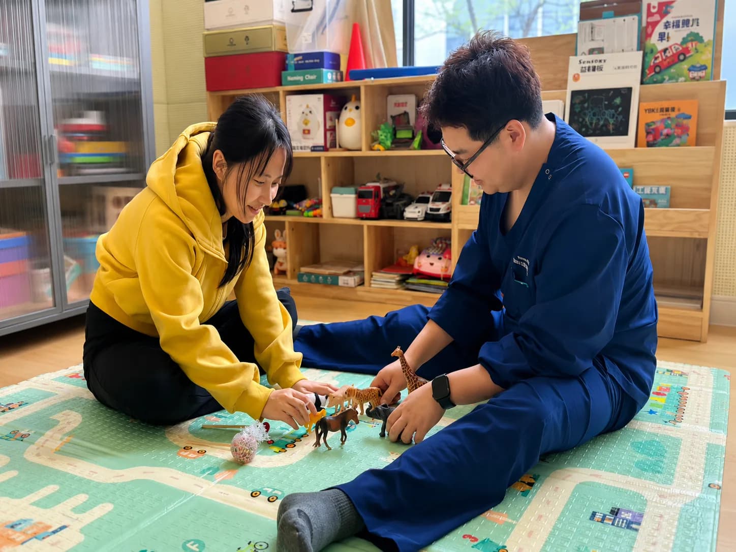 An Hanshi NeuroLife specialist plays with a child using figurines on a floor mat during a DIR/Floortime session