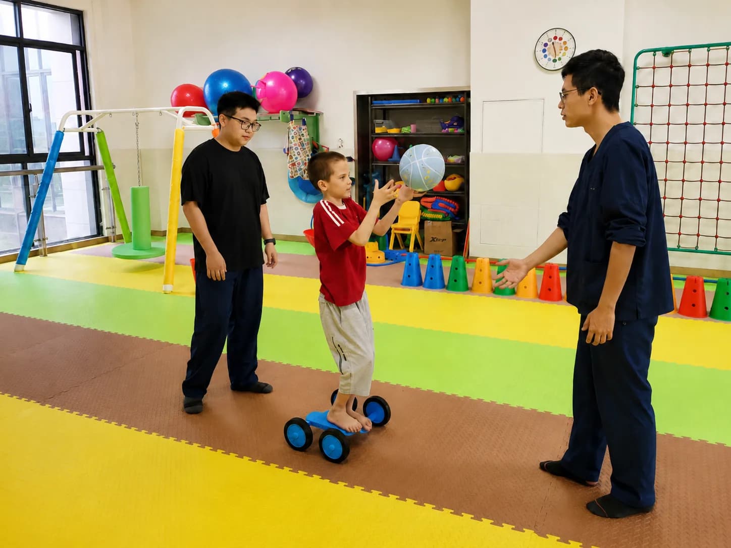 A child exercises on a balance trainer guided by specialists during a sensory integration session